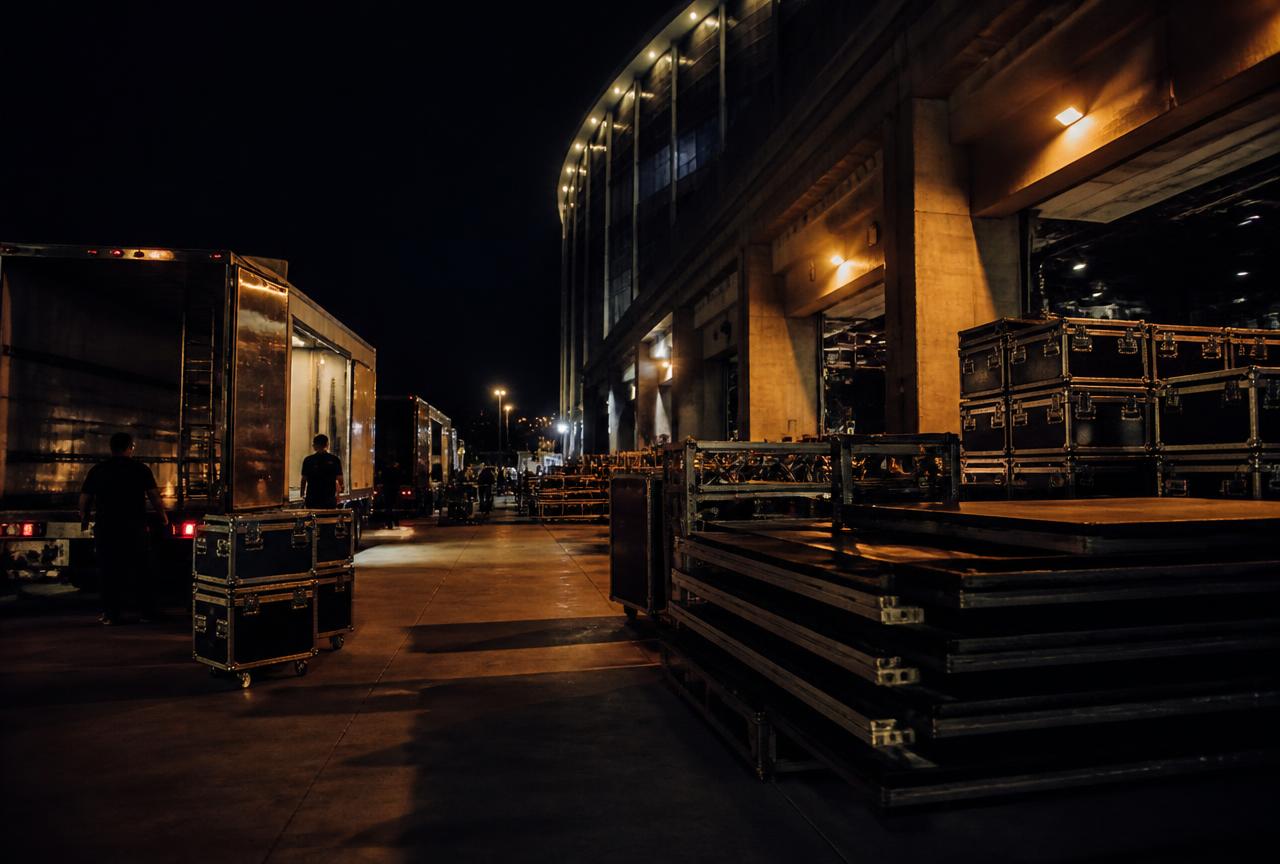 Arena loading bay at night with trucks, staging and flight cases